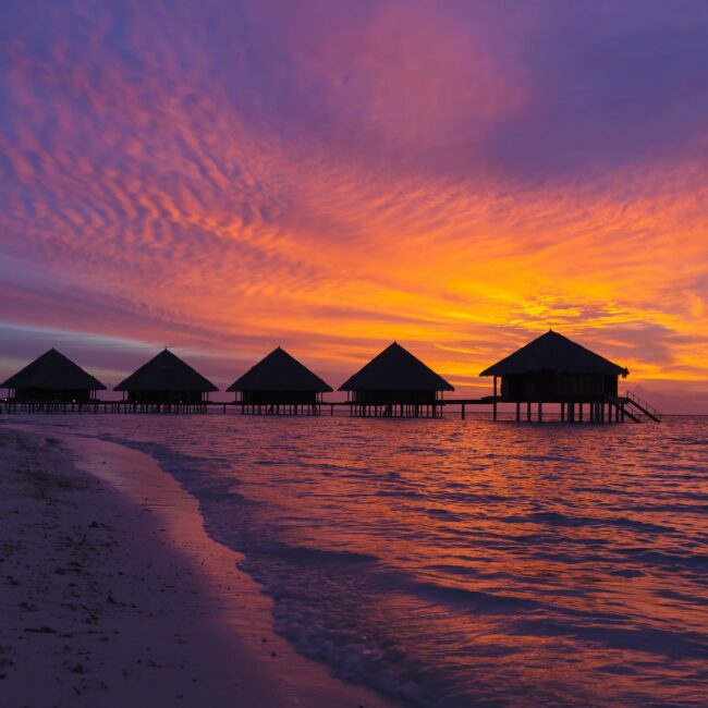 Sunset in the Maldives with a view of the lagoon and bungalows